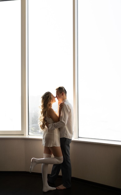 Photo un jeune couple amoureux le matin dans des vêtements décontractés se tient près de la fenêtre