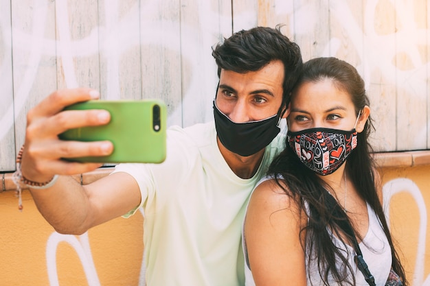 Jeune couple amoureux portant un masque facial prend un selfie avec un téléphone portable Copiez l'espace