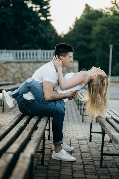 Un jeune couple amoureux posant sur le banc du parc