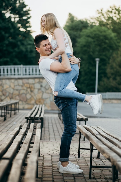 Un jeune couple amoureux posant sur le banc du parc