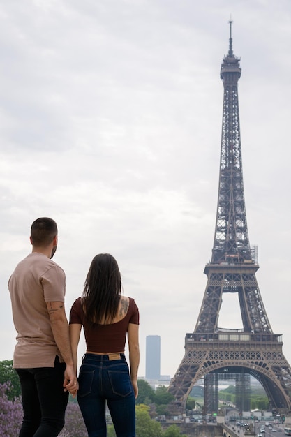 Jeune couple amoureux regardant de loin la tour eiffel à paris