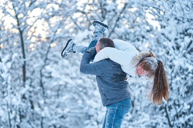 Un jeune couple amoureux s'amusant dans les bois d'hiver jouant et se jetant de la neige