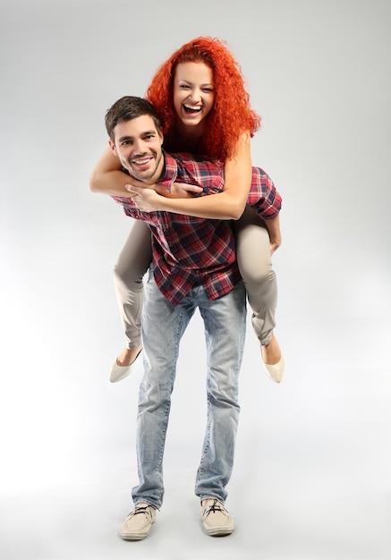 Jeune couple amoureux s'amusant sur fond gris