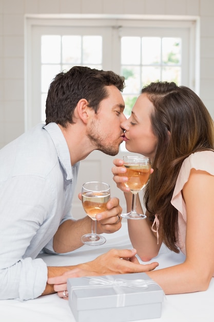 Jeune couple d&#39;amoureux s&#39;embrasser avec des verres à vin