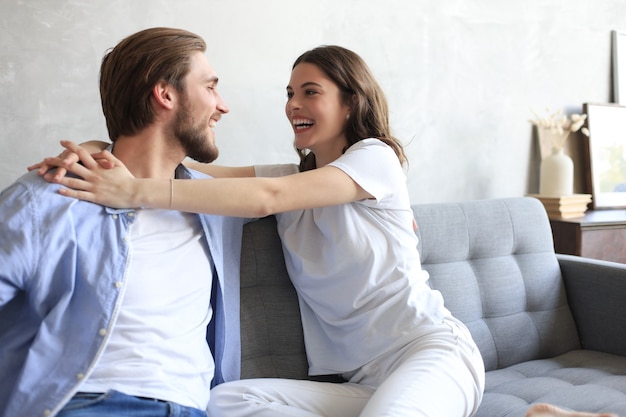 Jeune couple d'amoureux se détendre sur le canapé ensemble. La femme et l'homme s'embrassent et profitent de la compagnie l'un de l'autre assis sur un canapé, main dans la main, ayant un rendez-vous romantique.