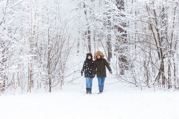 Jeune couple amoureux se promène dans la forêt enneigée. Vacances d'hiver actives.