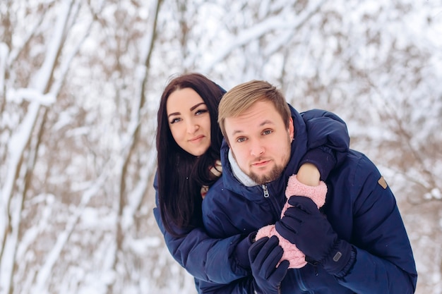 Jeune couple amoureux se promène dans la forêt d'hiver, gros plan portrait d'un gars et une fille dans une forêt enneigée,