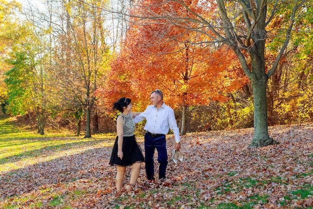 Jeune couple amoureux tenant par la main et se promener dans un parc sur une journée ensoleillée d&#39;automne