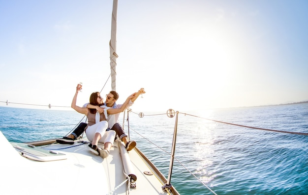 Jeune couple amoureux sur voilier avec champagne au coucher du soleil