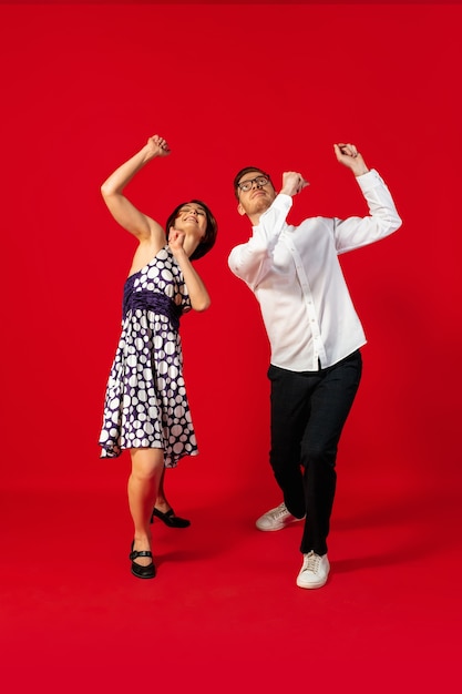 Jeune couple à l'ancienne danse isolé sur fond rouge