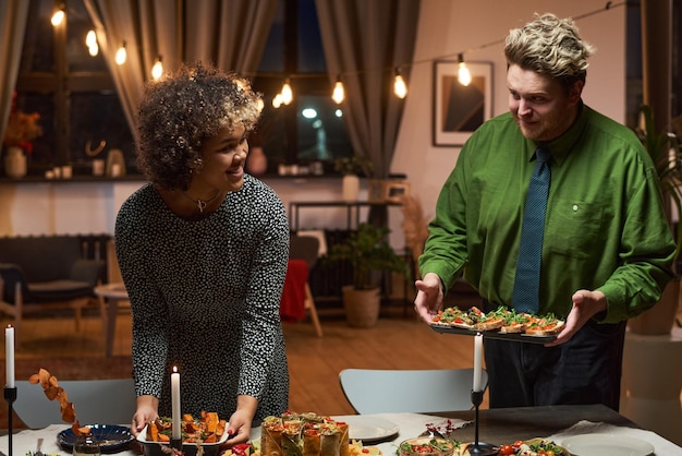 Jeune couple apéritifs sur table à manger ils organisent un dîner pour les amis