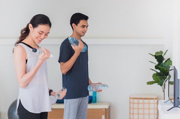 Un jeune couple asiatique fait de l'exercice ensemble à la maison. Concept d'exercice pendant la quarantaine à la maison pour prévenir l'infection par le coronavirus et le covid-19.