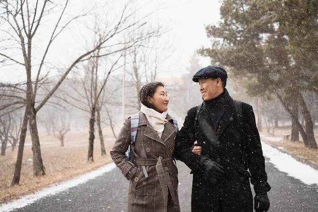 Un jeune couple asiatique heureux et amoureux se promène dans le parc de la ville d'hiver.