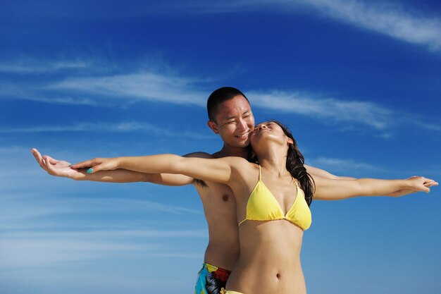 Un jeune couple asiatique heureux apprécie l'été et a sur une belle plage de sable blanc