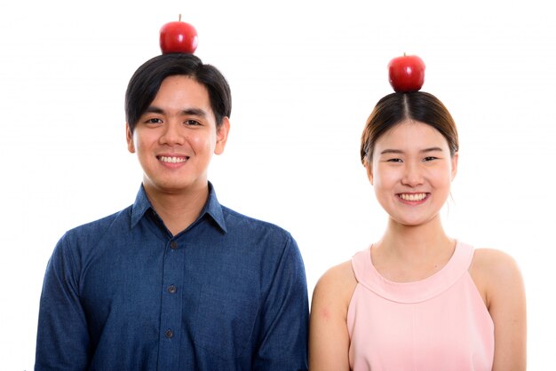 Jeune couple asiatique heureux souriant avec pomme rouge sur la tête ensemble