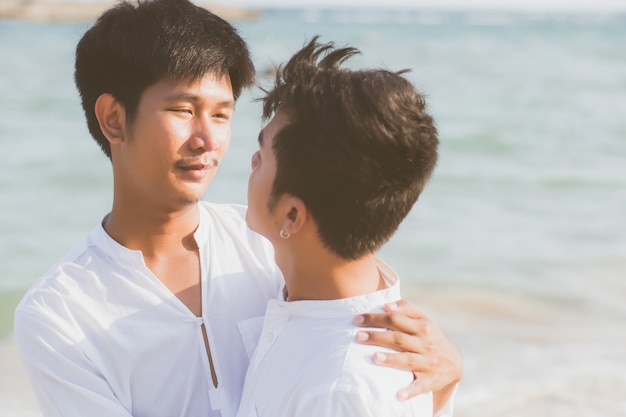 Jeune couple asiatique homosexuel debout câlin ensemble sur la plage en été