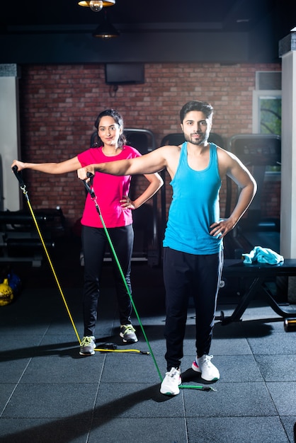 Jeune couple asiatique indien faisant de l'exercice avec une bande de résistance dans la salle de sport