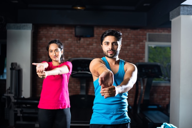 Jeune couple asiatique indien sportif s'étirant dans la salle de gym après l'exercice pour se rafraîchir, améliorer la flexibilité