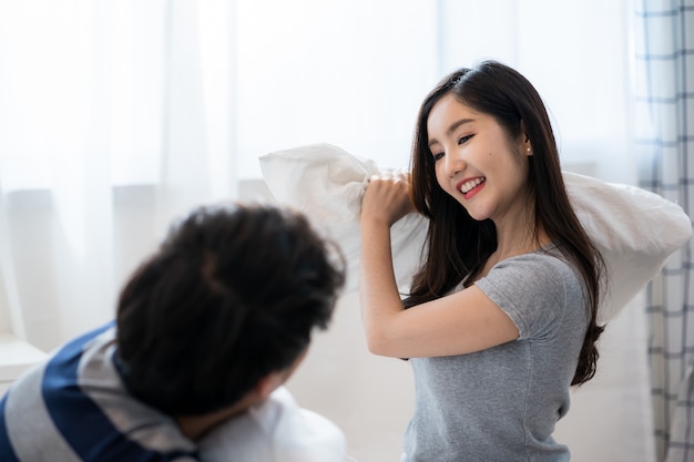 Jeune Couple Asiatique Jouant Joyeusement Avec Des Oreillers Sur Le Lit Ensemble, Saint-valentin