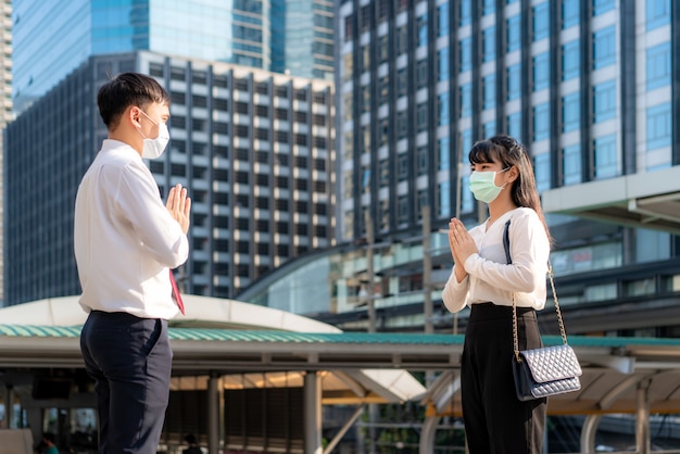 Jeune couple asiatique avec des masques stériles se salue