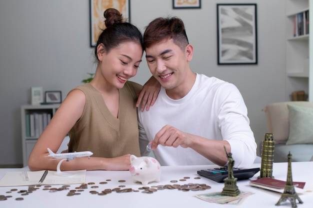 Un jeune couple asiatique prévoit d'économiser de l'argent pour un voyage autour du monde Concept de budget de voyage Modèle de monument de passeport et jouet d'avion sur la photo