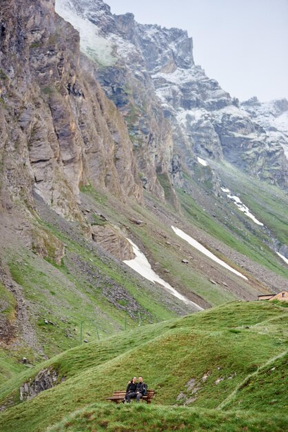 Jeune couple assis sur un banc dans les montagnes.