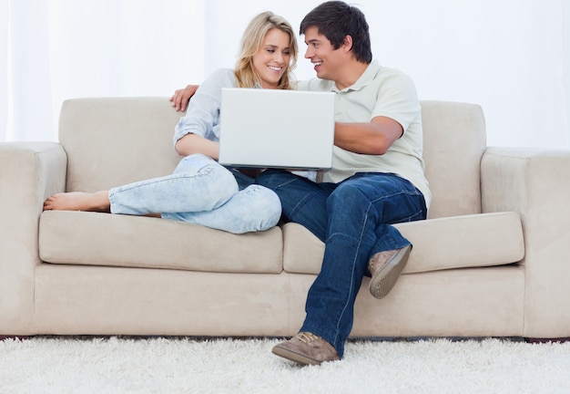 Un jeune couple assis sur un canapé avec un ordinateur portable