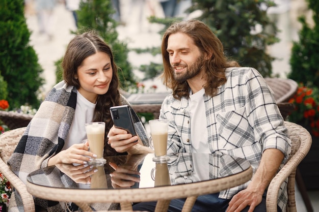 Jeune couple assis dans un café à l'extérieur en profitant du café et de la conversation