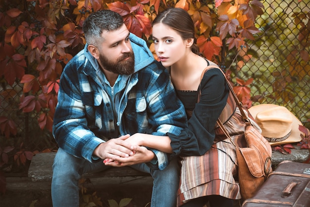 Jeune couple assis à l'extérieur au parc de l'automne.