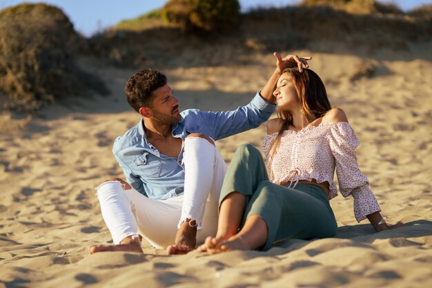 Photo un jeune couple assis sur la plage.