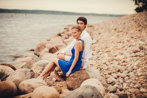 Jeune couple assis sur les rochers près de l&#39;eau