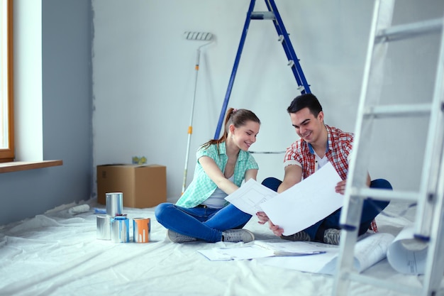 Jeune couple assis sur le sol et calculant leurs économies