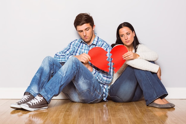 Jeune couple assis sur le sol avec le cœur brisé