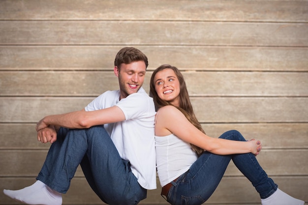 Jeune couple assis sur le sol contre une surface en bois avec des planches
