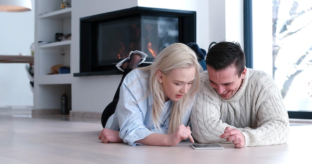 Jeune couple assis sur le sol et utilisant Internet sur tablette numérique