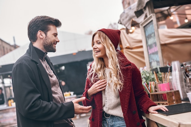 Jeune couple en attente d'un barista en se tenant devant le comptoir du bar