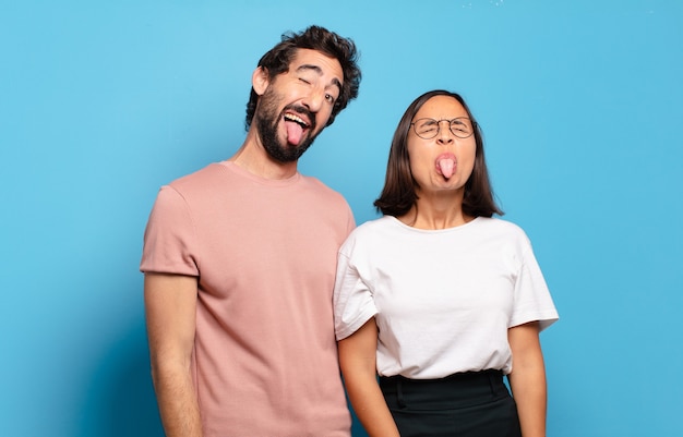 Jeune couple avec une attitude joyeuse, insouciante et rebelle, plaisantant et tirant la langue, s'amusant