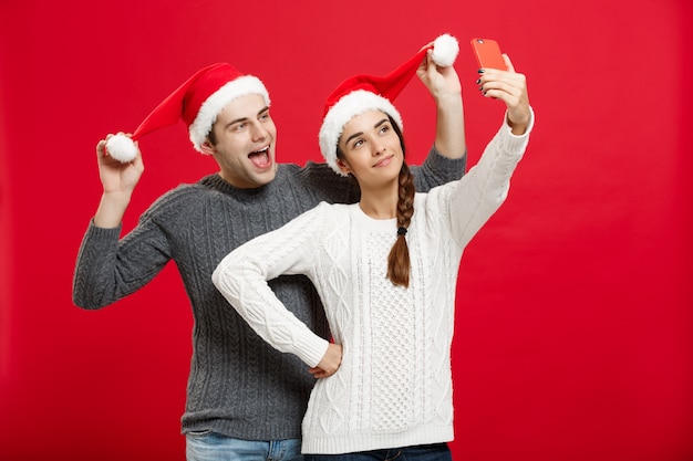Jeune couple attrayant prenant un selfie par téléphone portable célébrant le jour de Noël.