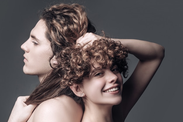 Jeune couple aux cheveux ondulés longs et brillants qui pose en studio. Coupe de cheveux de mode.