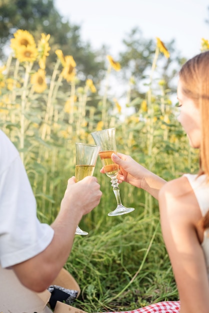 Jeune couple ayant pique-nique sur le champ de tournesol au coucher du soleil