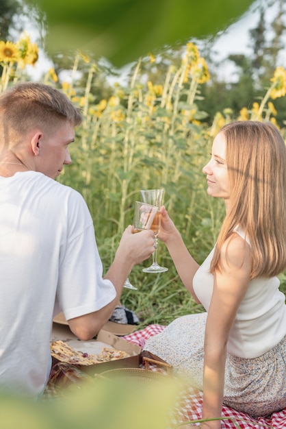 Jeune couple ayant pique-nique sur le champ de tournesol au coucher du soleil