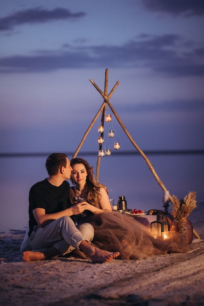 Jeune couple ayant un pique-nique sur la plage d'un lac rose