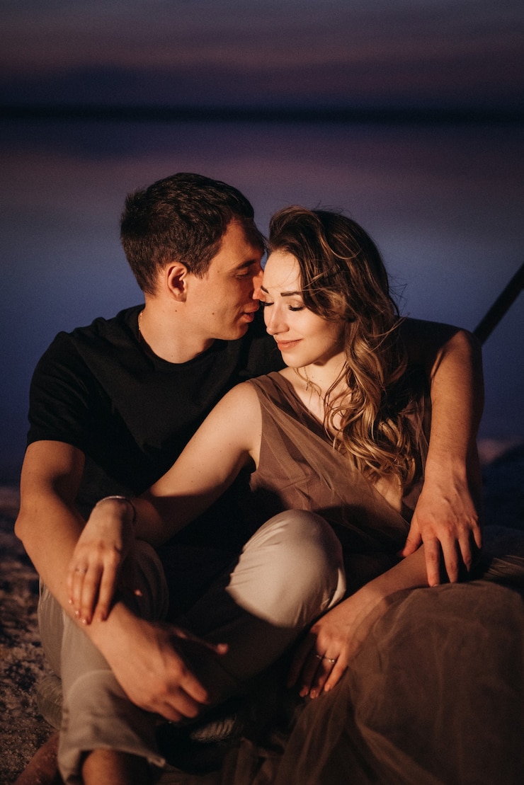 Photo jeune couple ayant un pique-nique sur la plage d'un lac rose