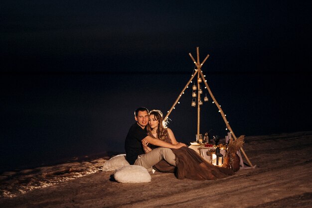 Jeune couple ayant un pique-nique sur la plage d'un lac rose