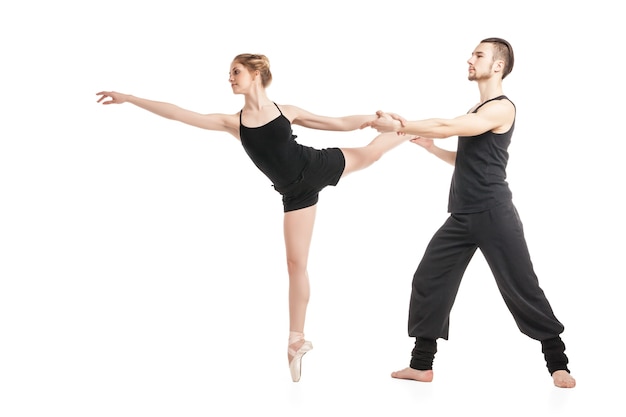 Jeune couple de ballet en danse noire contre de fond blanc. Isolé