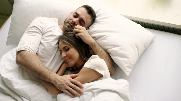 Jeune couple beau et aimant s'embrasser et s'embrasser dans son lit en se réveillant le matin