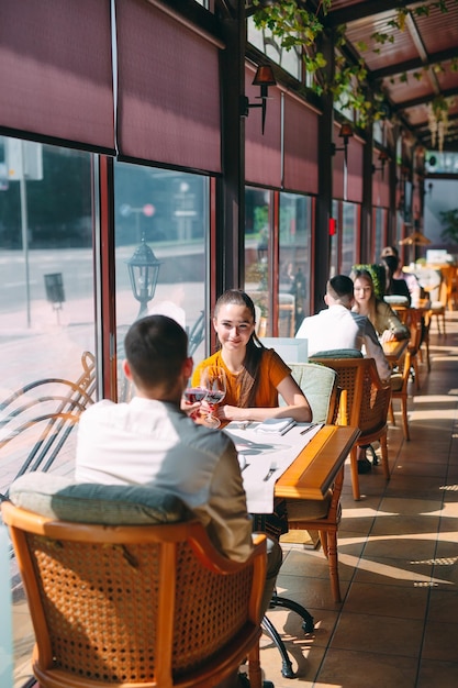 Un jeune couple boit du vin dans un restaurant près de la fenêtre.