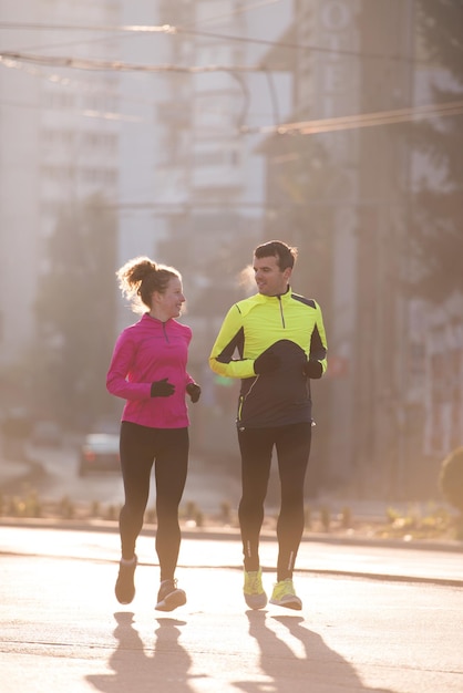 jeune couple en bonne santé faisant du jogging dans la ville tôt le matin avec le lever du soleil en arrière-plan