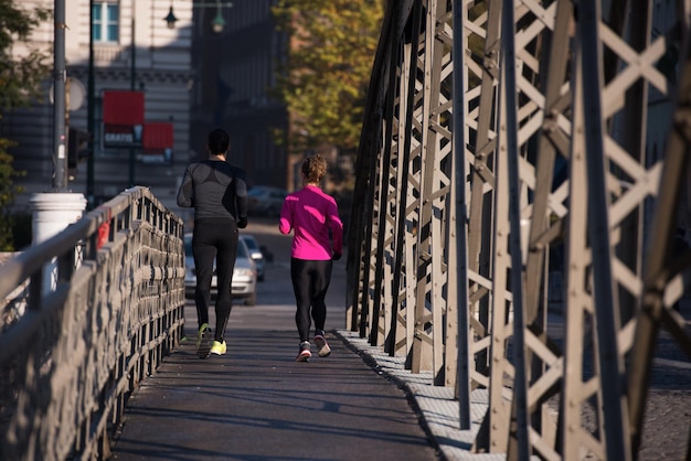 jeune couple en bonne santé faisant du jogging dans la ville tôt le matin avec le lever du soleil en arrière-plan