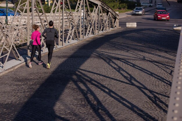 jeune couple en bonne santé faisant du jogging dans la ville tôt le matin avec le lever du soleil en arrière-plan